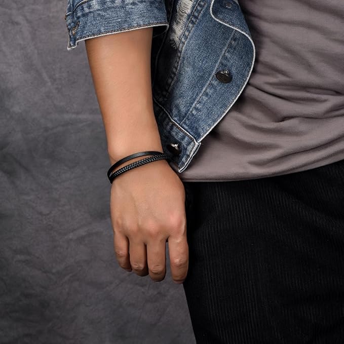 Person wearing a denim jacket and black bracelet on a gray background