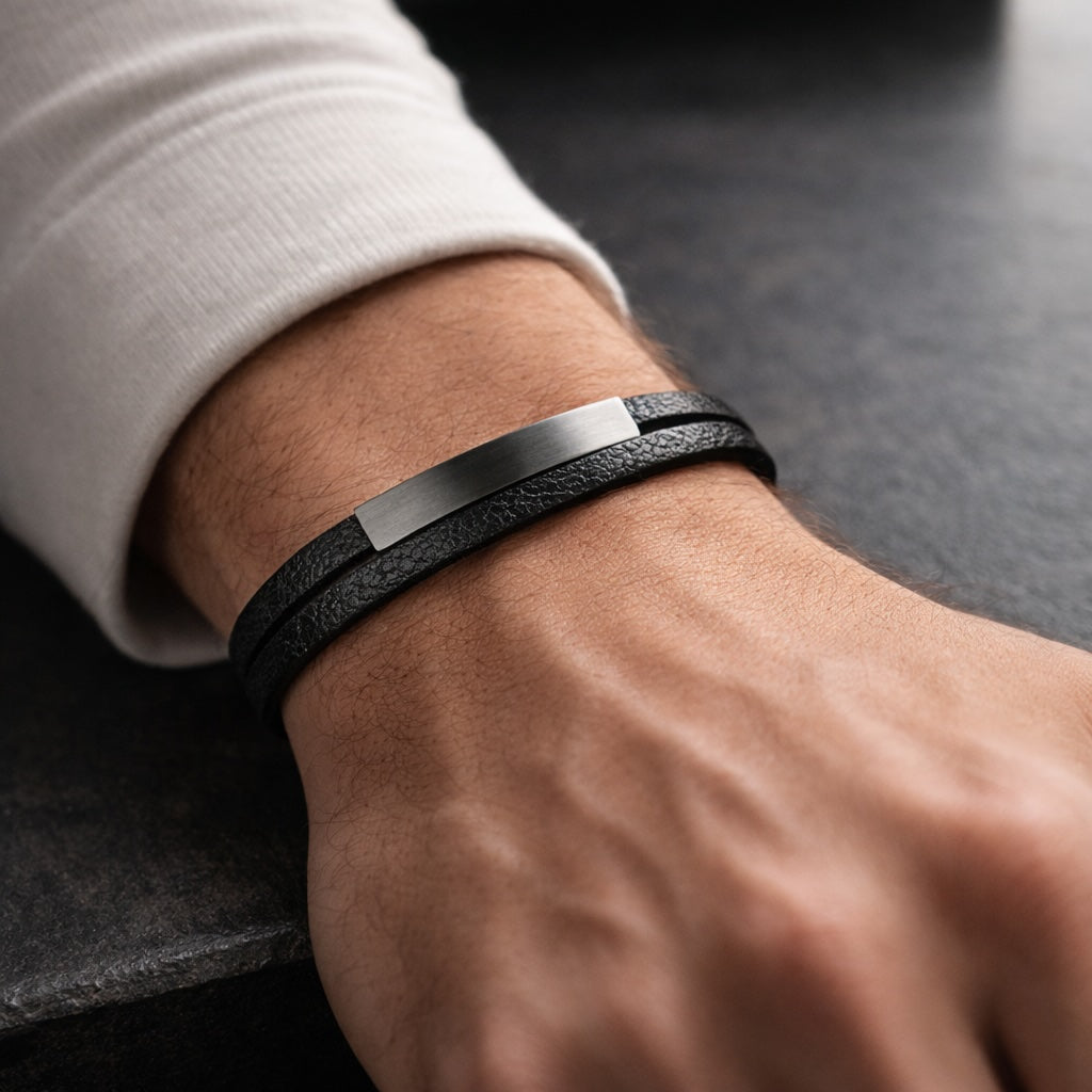 Black leather bracelet with metallic clasp on a wrist against a dark background