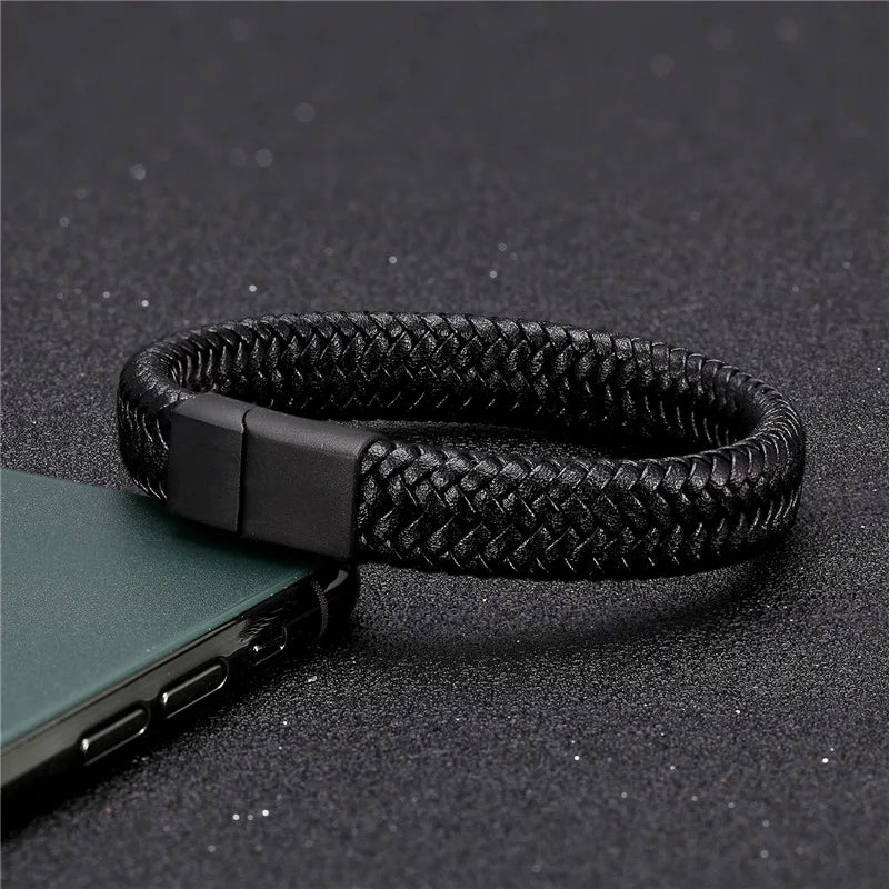 Black braided leather bracelet on a dark textured surface