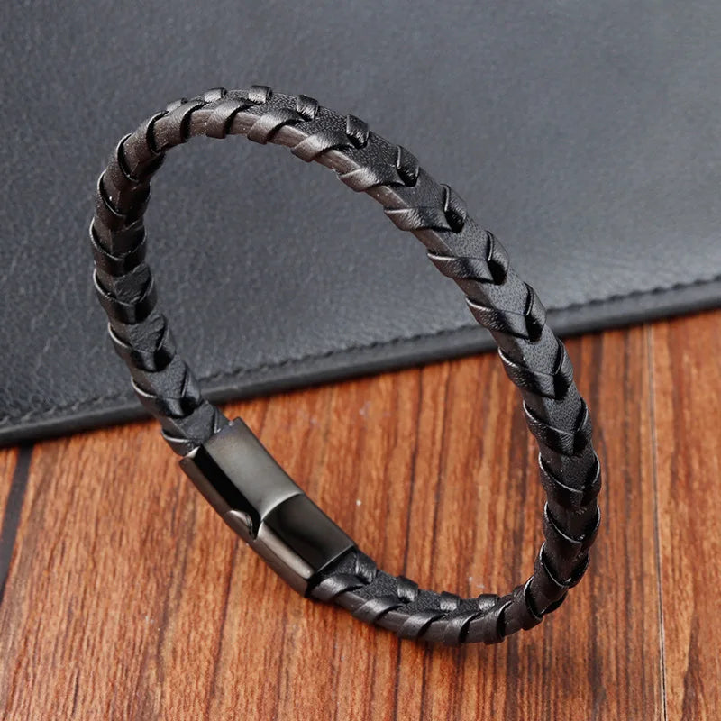 Black braided leather bracelet on a wooden surface with a dark gray background