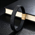 Black leather bracelet with metallic clasp on a book