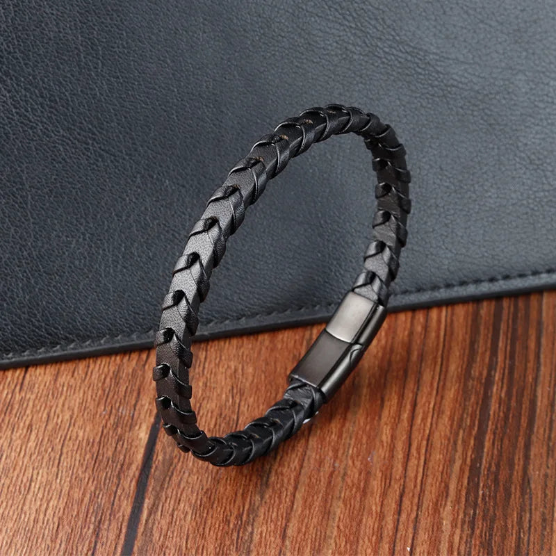 Black braided leather bracelet with metal clasp on a wooden surface