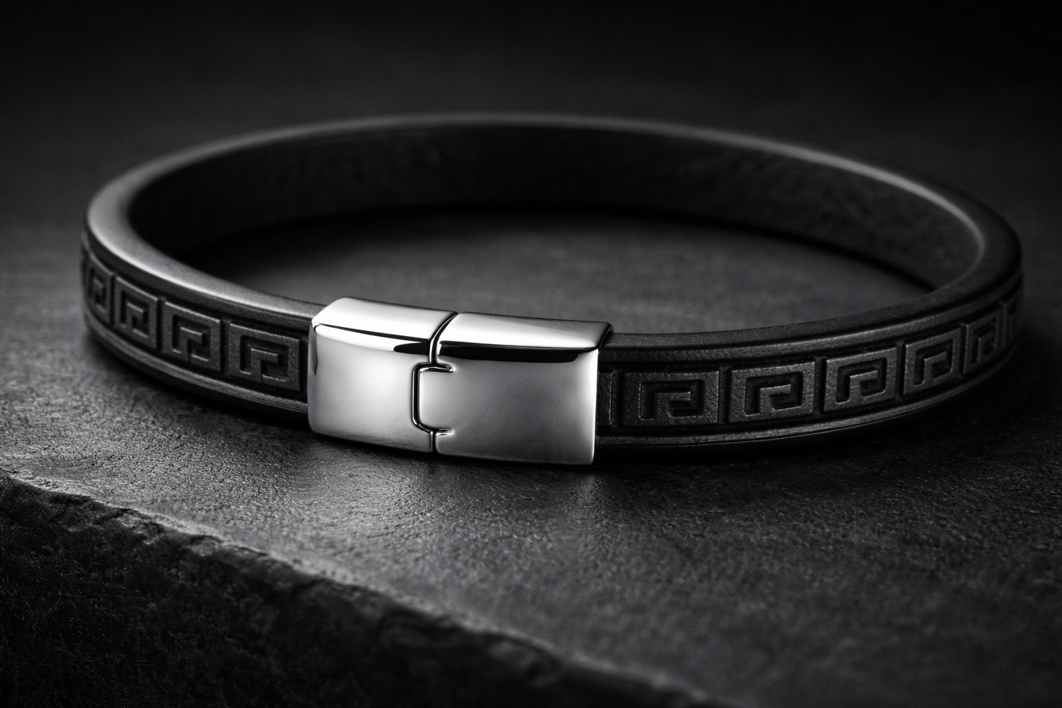 Black leather bracelet with a silver clasp on a dark background