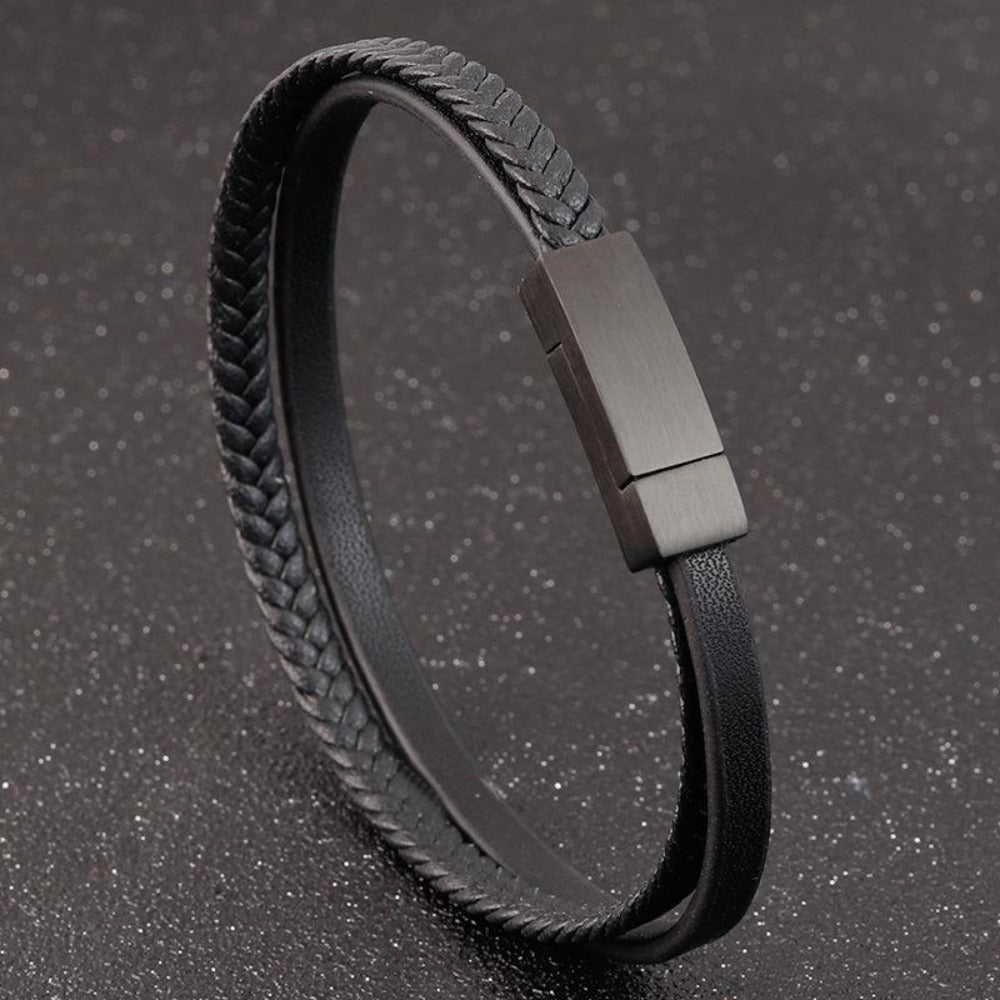 Black braided leather bracelet with a metallic clasp on a dark textured background