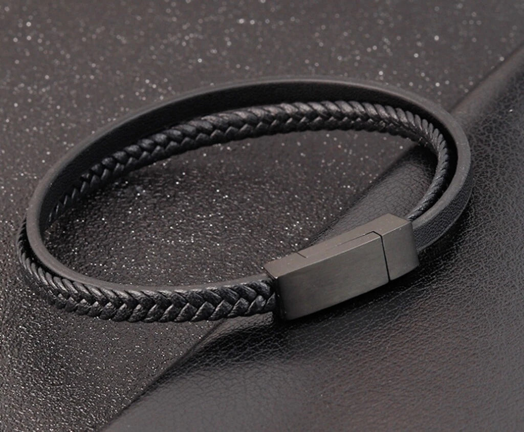 Black braided leather bracelet with a metallic clasp on a dark textured background